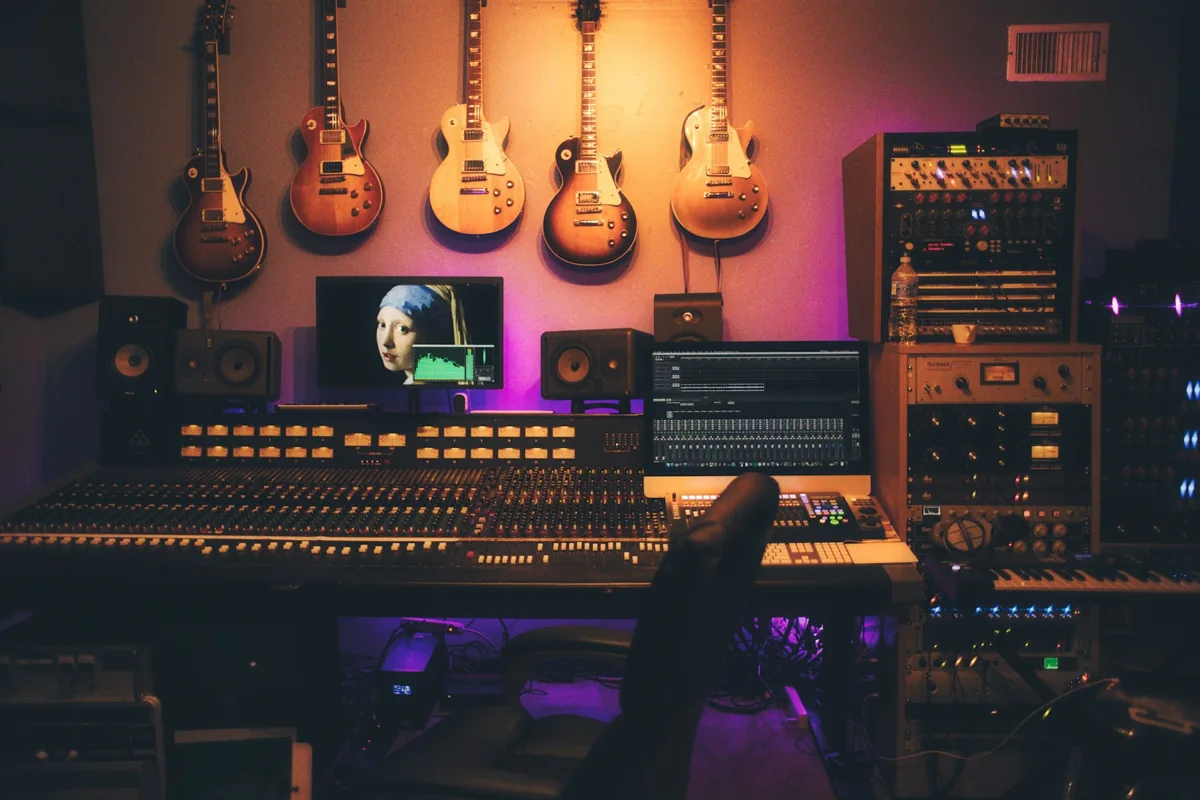 A warm recording studio with guitars, speakers and a mixing desk
